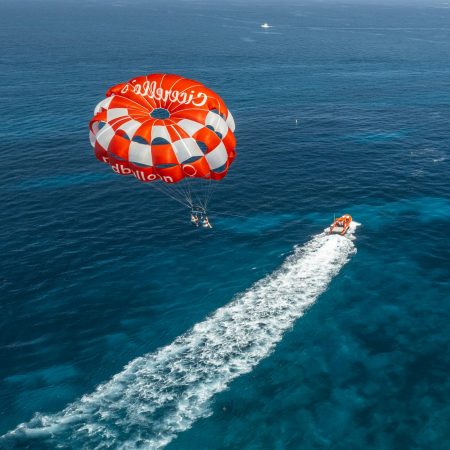 Aerial view of parasailing adventure over clear blue ocean.