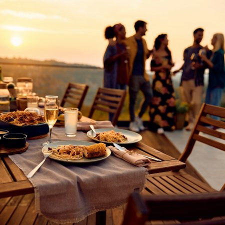 Dining table on a terrace at sunset with people in the background.