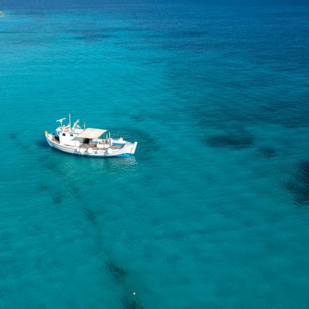 Greece, Cyclades. Aerial drone view of a fishing boat on turquoise color sea water