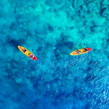 Kayaking. Aerial view of floating kayaks and people on blue sea at sunny day.