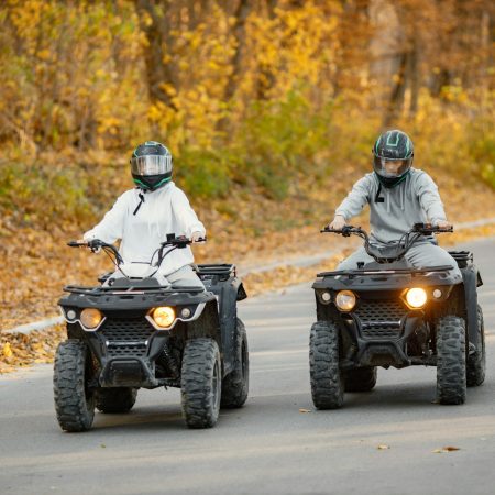 Man and woman driving quad bikes in autumn forest