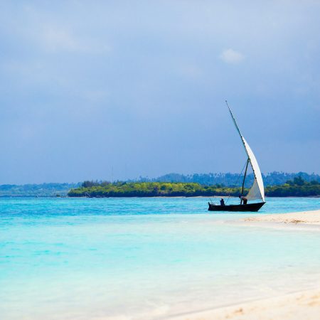 Old wooden dhow on white beach in the Indian Ocean