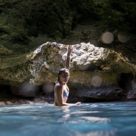 Woman swimming in a serene cave pool.