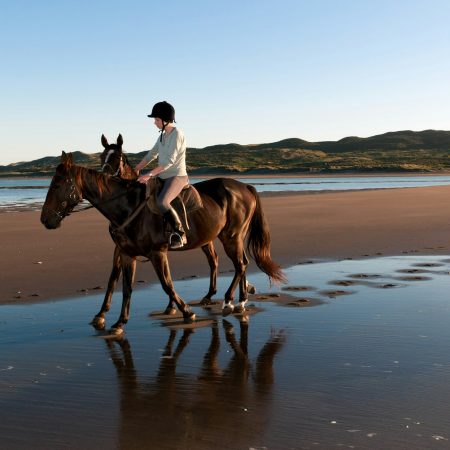 Young woman riding horse on beach